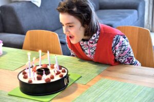 Dievča sfukuje sviečky na narodeninovej torte.